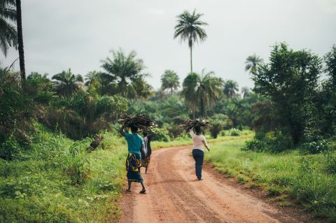 Strasse in Sierra Leone mit Menschen die Brennholz befördern