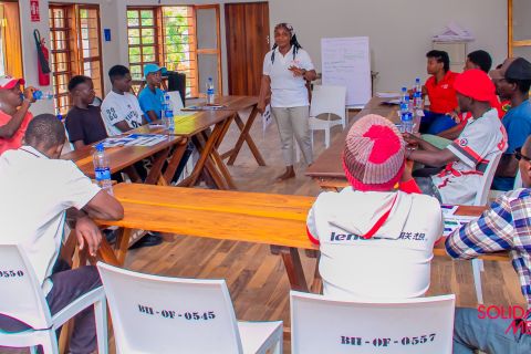Beatrice Chiyokoma steht vor einer Gruppe junger Menschen in einem Schulungsraum und spricht über mentale Gesundheit.